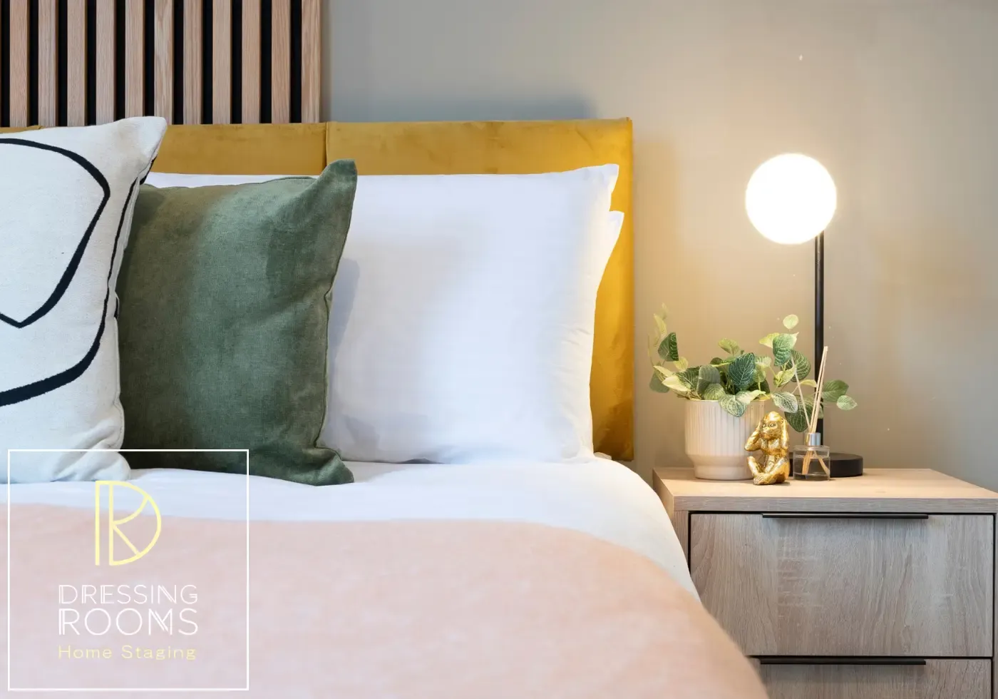 Bed styling detail with green cushions and globe light